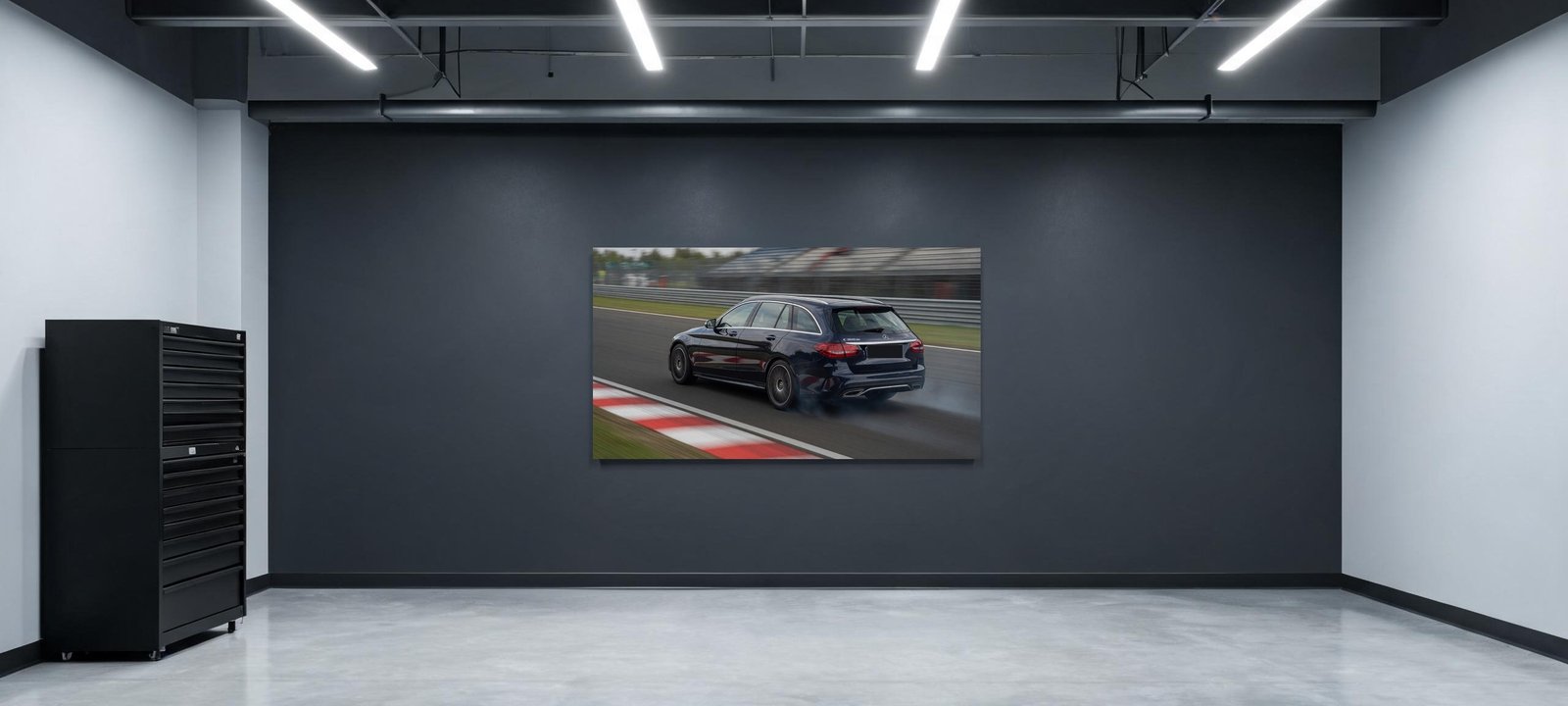 Garage mit einer großen Leinwand an der Wand, darauf ein dunkelblauer Mercedes C-Klasse Kombi auf der Rennstrecke